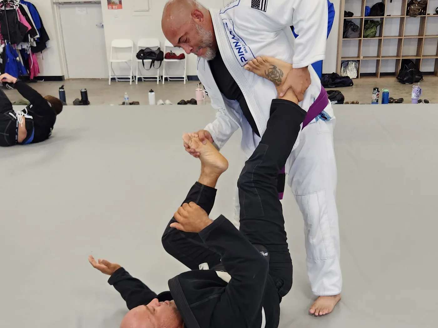 An instructor working from guard with a student during an adult class at Pinnacle Brazilian Jiu Jitsu