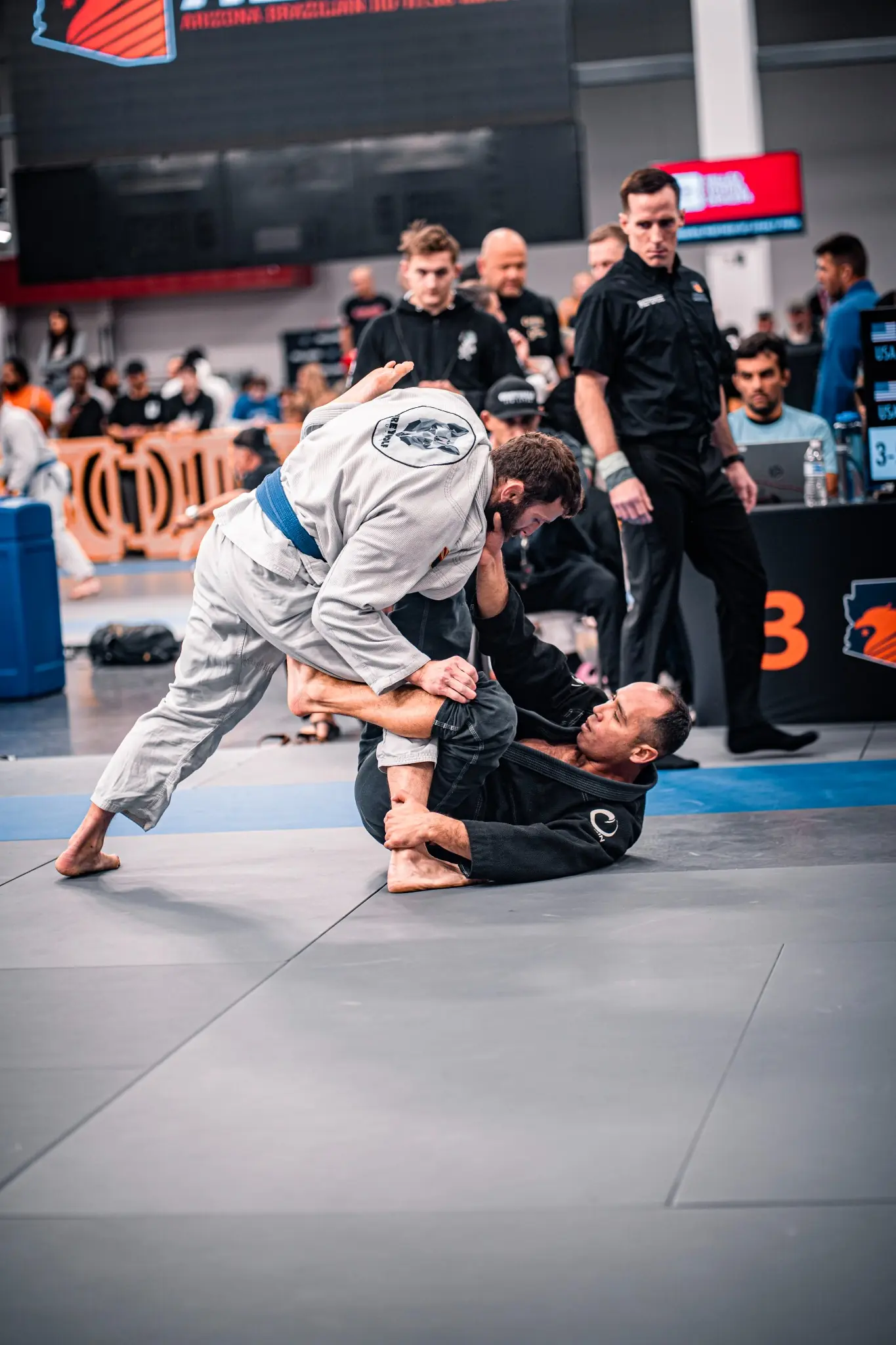 Two athletes competing in a Brazilian Jiu Jitsu tournament match