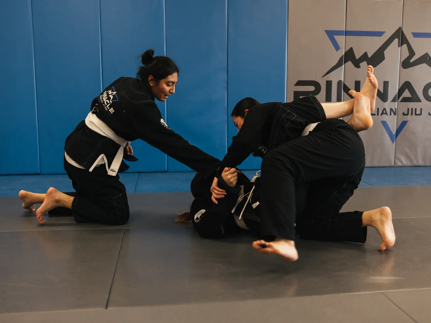 Three women drilling a self-defense technique together during a women&rsquo;s class at Pinnacle Brazilian Jiu Jitsu